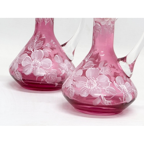 465 - A pair of Early 20th Century painted cranberry glass cruets. 17cm