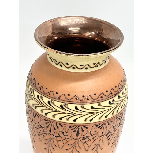 715B - A terracotta vase with lustre glazed interior and embossed enamel paintwork. 25cm