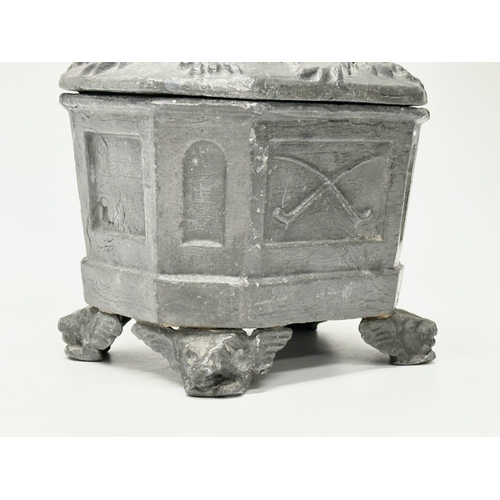 312 - An Early 19th Century English George III lead tobacco box. Depicting smokers pipes, four griffin fee... 