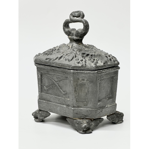 312 - An Early 19th Century English George III lead tobacco box. Depicting smokers pipes, four griffin fee... 
