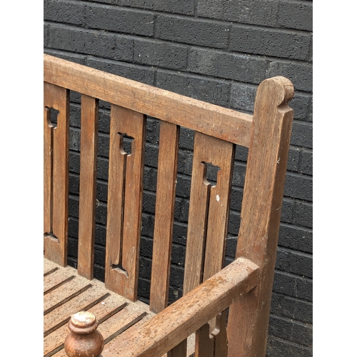 8 - A large Arts & Crafts style teak garden bench. 183x108cm