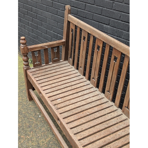 8 - A large Arts & Crafts style teak garden bench. 183x108cm