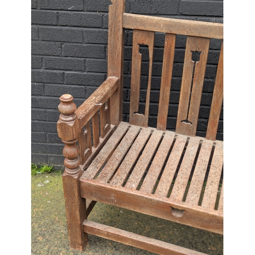 8 - A large Arts & Crafts style teak garden bench. 183x108cm
