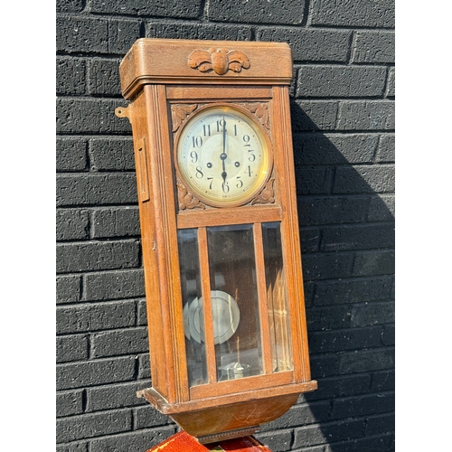 372 - A 1930’s oak cased wall clock. With pendulum and key. 78cm.