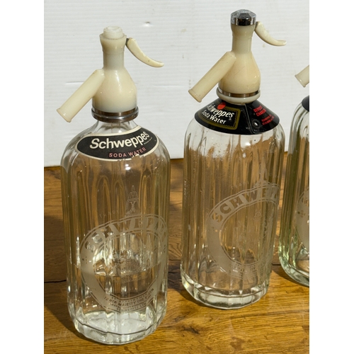 251 - Four vintage Schweppes soda syphons. 30cm.