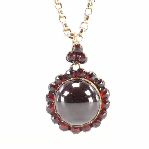 215 - An antique garnet locket on a gold chain. The Victorian locket being set with central garnet cabocho... 