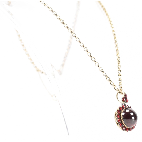 215 - An antique garnet locket on a gold chain. The Victorian locket being set with central garnet cabocho... 