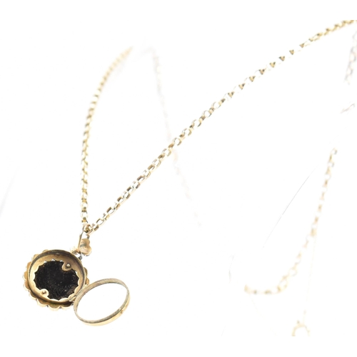 215 - An antique garnet locket on a gold chain. The Victorian locket being set with central garnet cabocho... 