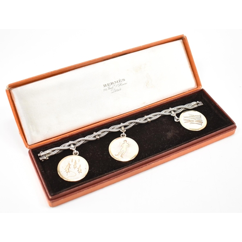 224 - A vintage Hermès silver skiing medallion bracelet. The bracelet constructed from three woven chains ... 