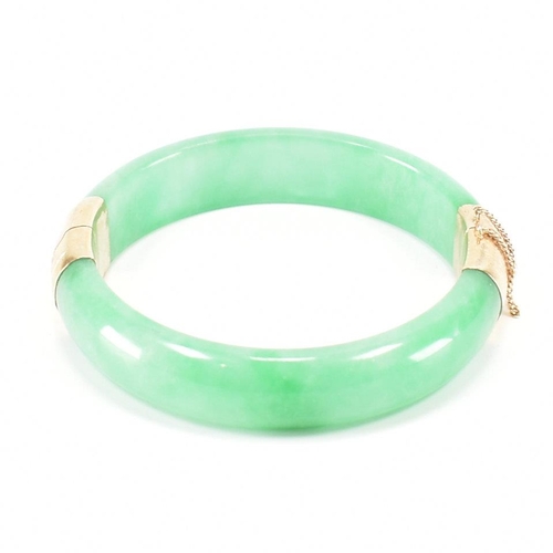 226 - A vintage green jade and gold plated bangle bracelet. The bracelet having gold plated fittings with ... 