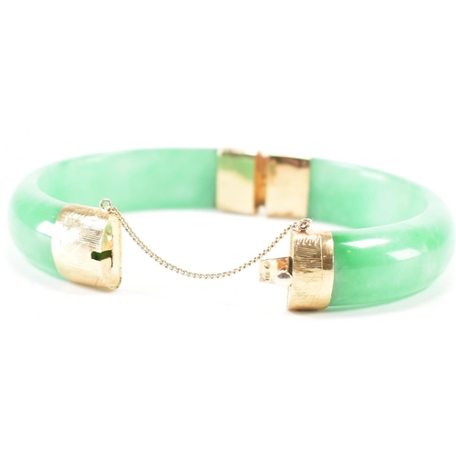 226 - A vintage green jade and gold plated bangle bracelet. The bracelet having gold plated fittings with ... 