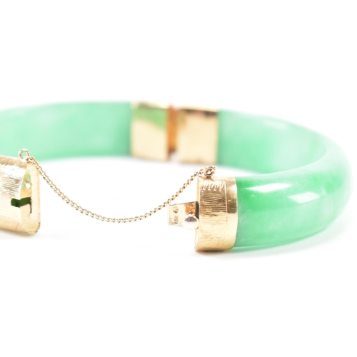 226 - A vintage green jade and gold plated bangle bracelet. The bracelet having gold plated fittings with ... 