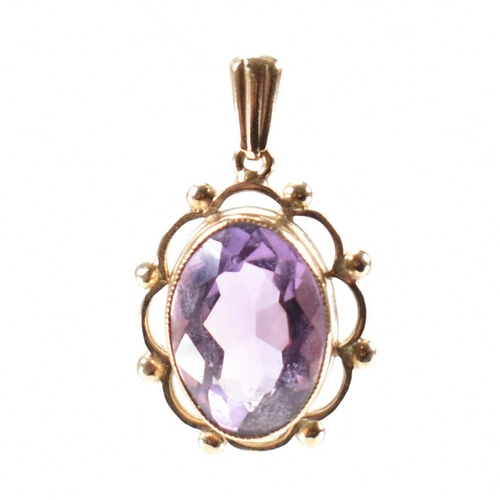 232 - A hallmarked 9ct gold and purple stone pendant. The necklace pendant having a central bezel faceted ... 