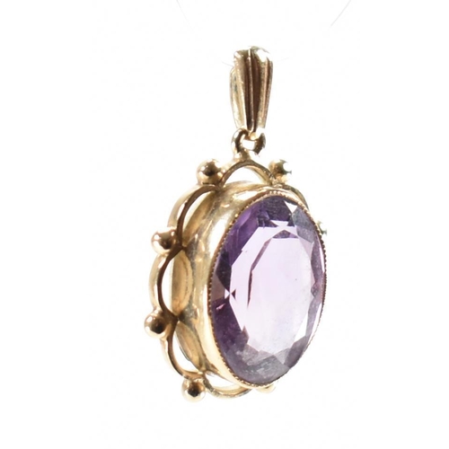 232 - A hallmarked 9ct gold and purple stone pendant. The necklace pendant having a central bezel faceted ... 