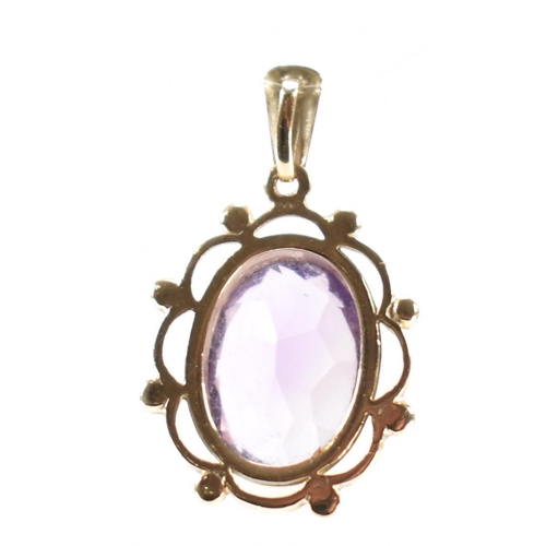 232 - A hallmarked 9ct gold and purple stone pendant. The necklace pendant having a central bezel faceted ... 