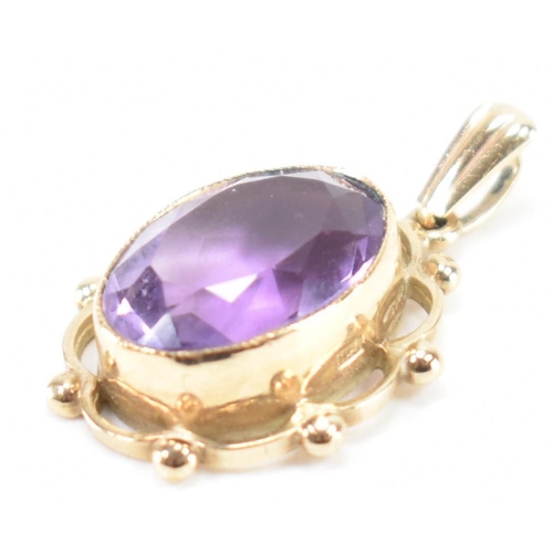 232 - A hallmarked 9ct gold and purple stone pendant. The necklace pendant having a central bezel faceted ... 