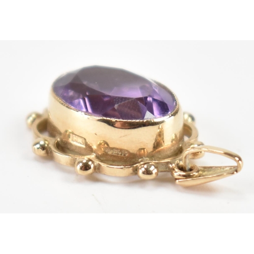 232 - A hallmarked 9ct gold and purple stone pendant. The necklace pendant having a central bezel faceted ... 