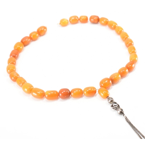 249 - An antique amber and silver necklace. The necklace being strung with twenty five barrel shaped beads... 