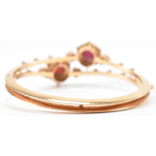 287 - An 18ct gold garnet and pearl bangle. The bracelet having twin knife bar mount with 2 garnet and pea... 