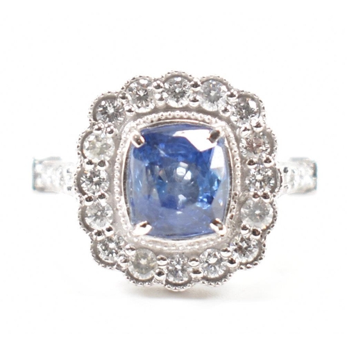 301 - A white gold sapphire and diamond halo ring. The ring set with a cushion cut sapphire surrounded fra... 