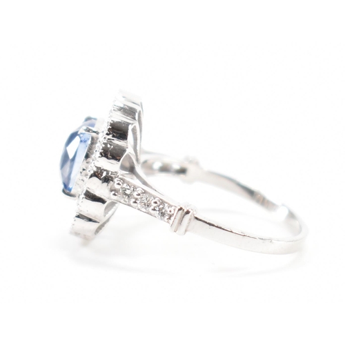 301 - A white gold sapphire and diamond halo ring. The ring set with a cushion cut sapphire surrounded fra... 