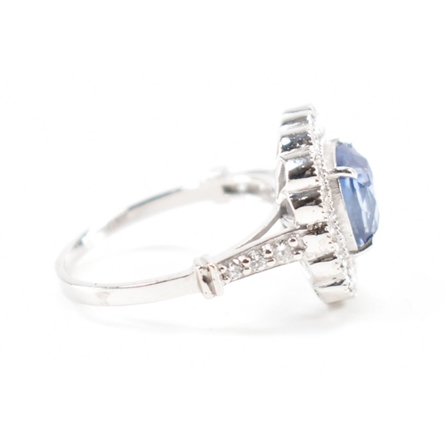 301 - A white gold sapphire and diamond halo ring. The ring set with a cushion cut sapphire surrounded fra... 