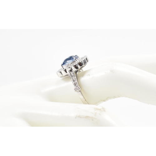 301 - A white gold sapphire and diamond halo ring. The ring set with a cushion cut sapphire surrounded fra... 