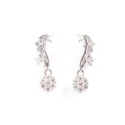 530A - A pair of hallmarked 18ct white gold and white stone earrings. The earrings of foliate form with rou... 