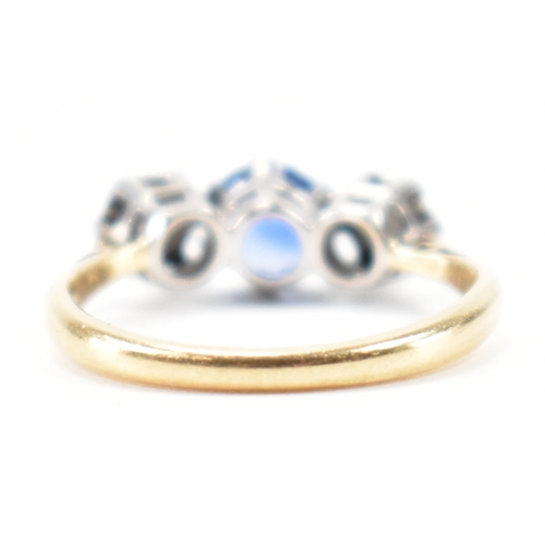 201 - An 18ct gold sapphire and diamond three stone ring. The ring being set with a round cut blue sapphir... 