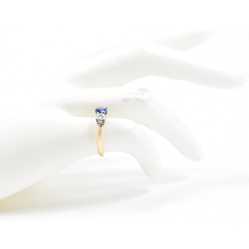 201 - An 18ct gold sapphire and diamond three stone ring. The ring being set with a round cut blue sapphir... 