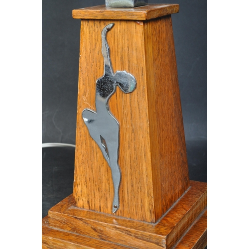 1155 - A 1930's Art Deco oak and chrome table lamp embellished with a chrome nude dancer silhouette  to one... 