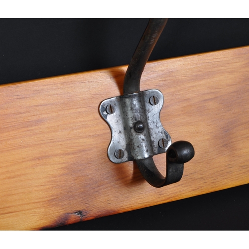 1165a - A 20th century coat rack rail having pine back board and a series of five white metal hooks.