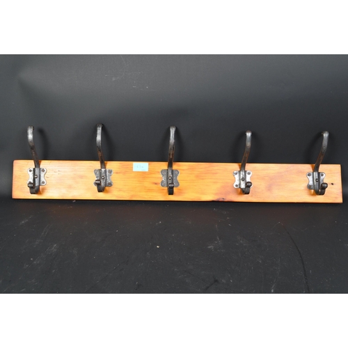 1165a - A 20th century coat rack rail having pine back board and a series of five white metal hooks.