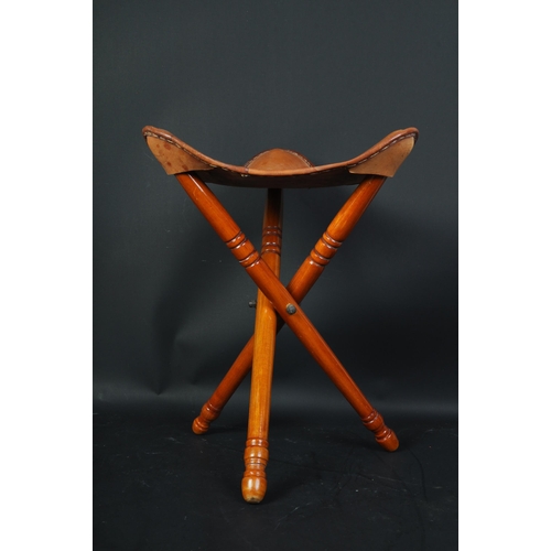 1378 - A 20th century leather and mahogany tripod stool. The stool with a studded leather top raised on fol... 