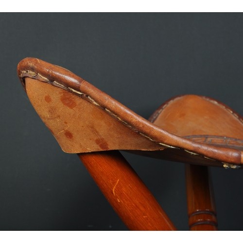 1378 - A 20th century leather and mahogany tripod stool. The stool with a studded leather top raised on fol... 