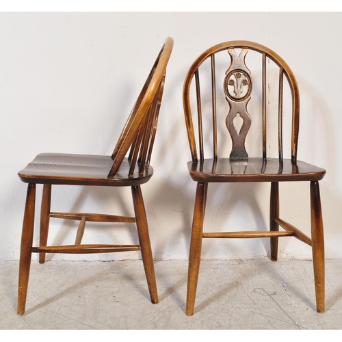 1387 - A Set of 20th century Ercol fleur de Lys beech and elm dining chairs with arched back rests, spindle... 