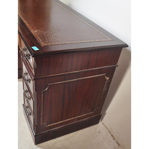 1451 - A 20th century George III style mahogany and leather twin pedestal office desk having a chamfered to... 