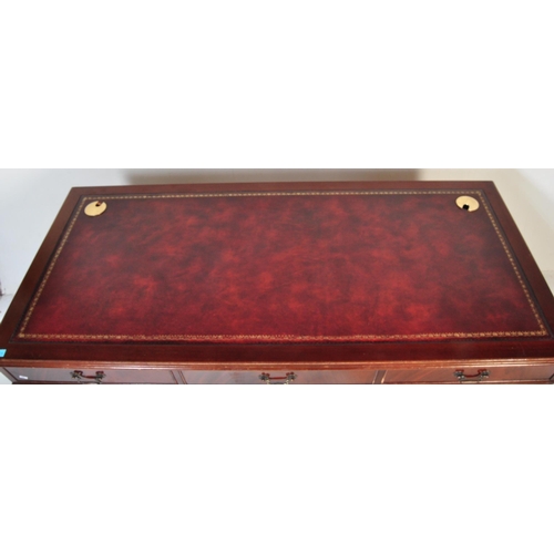 1482 - A 20th century mahogany twin pedestal writing desk. The desk having a red leather skiver to top over... 