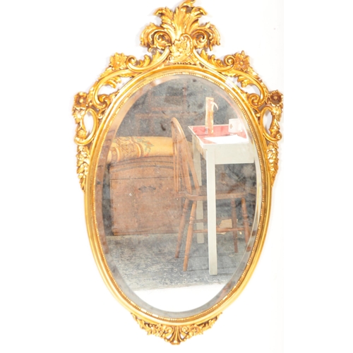 1504 - A Veronese product made in England. A gilt hanging wall mirror. Of oval form with scroll foliate dec... 