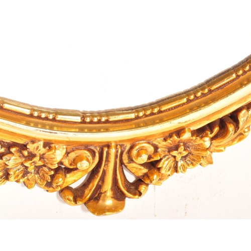 1504 - A Veronese product made in England. A gilt hanging wall mirror. Of oval form with scroll foliate dec... 