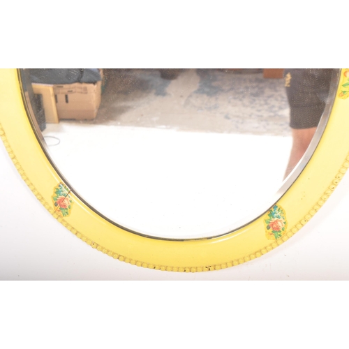 1523 - A yellow painted oval folk bevelled mirror. The mirror with a beaded decorated border with floral / ... 