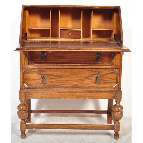 1578 - A 1920’s oak Jacobean revival bureau desk being raised on cup and cover legs with double drawers and... 