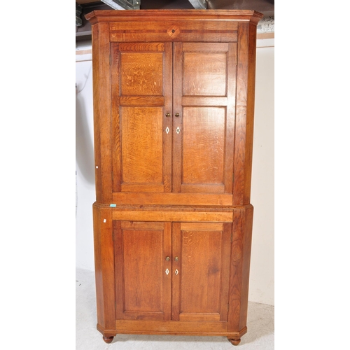 1591 - An 18th century George III country oak double corner cupboard. Raised on bracket feet with twin cupb... 