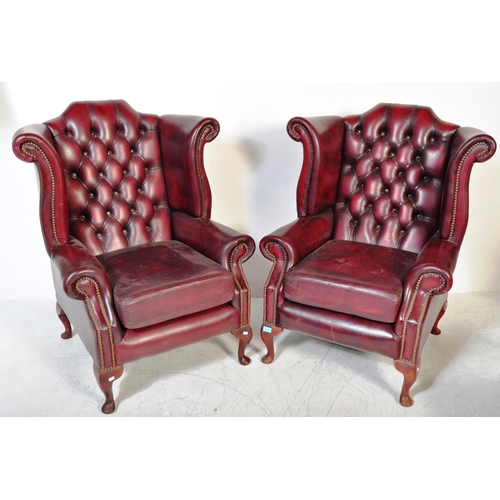 1613 - A pair of 20th Century Chesterfield - Queen Anne armchairs. In oxblood leather colour way with wing ... 