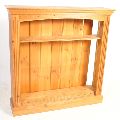 1658 - A vintage 20th century pine wood open faced bookcase having a flared straight top over an arched sha... 