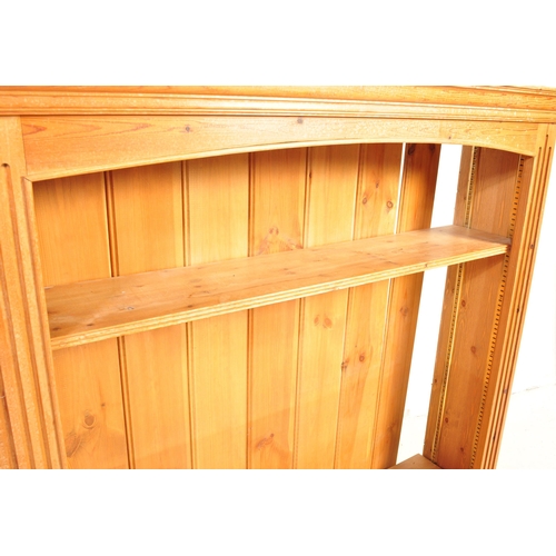 1658 - A vintage 20th century pine wood open faced bookcase having a flared straight top over an arched sha... 