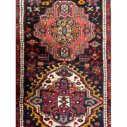 1558 - An early 20th century Heriz Persian Islamic runner floor carpet rug having a series of central polyc... 