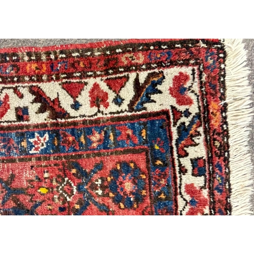 1560 - An early 20th century Persian Islamic Hamada runner floor carpet rug having a red ground central pan... 