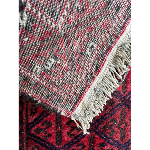 1565 - An vintage mid 20th century Persian Islamic Belouch floor carpet rug having a red background with re... 