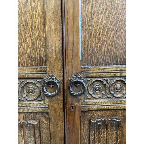 1660 - A vintage 20th century Jacobean Revival oak bedroom wardrobe having a flared top over two tall twin ... 